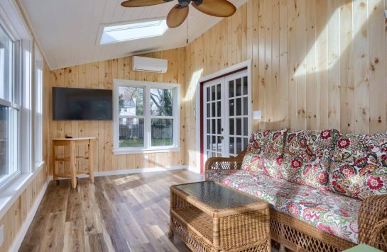 interior wood paneling on walls, ceiling, and floor with couch and mounted tv
