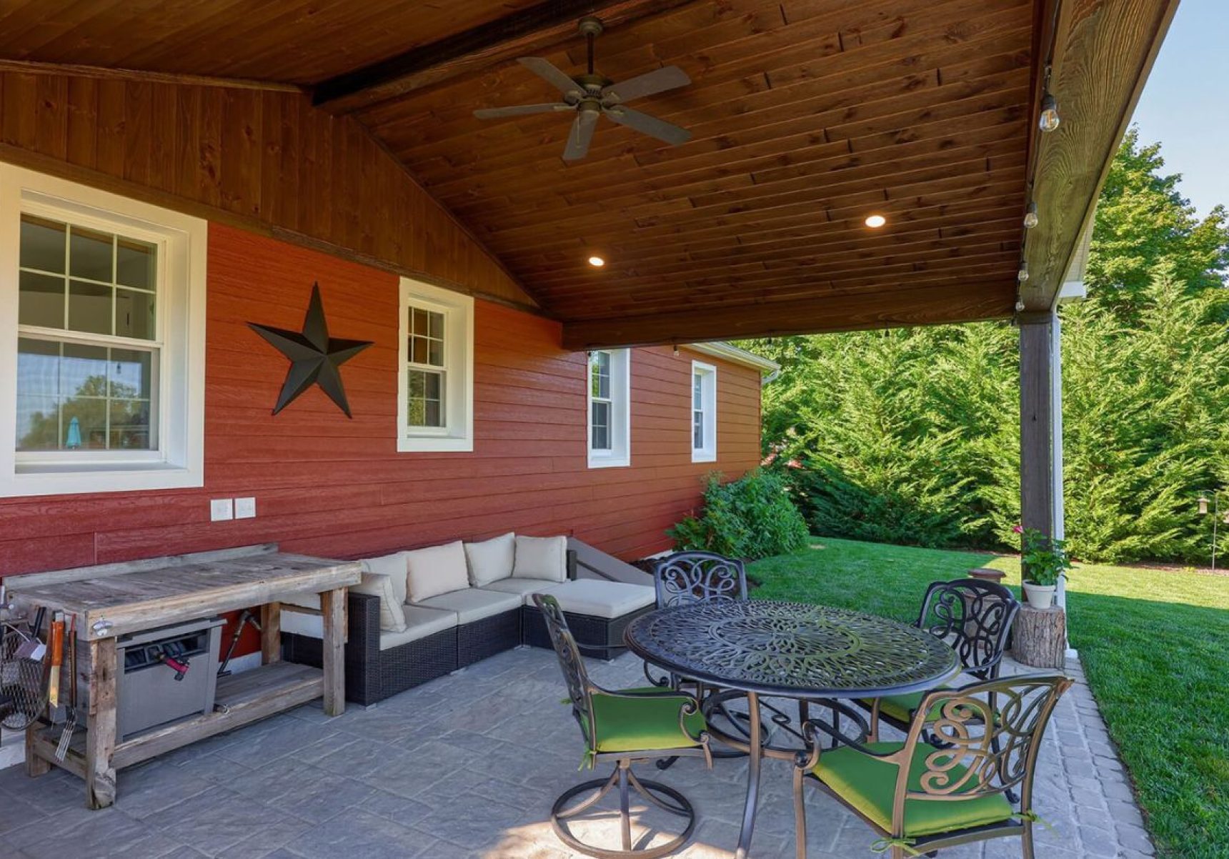 outdoor porch with outdoor furniture, wood paneling roofing, attached to house with red siding and white windows