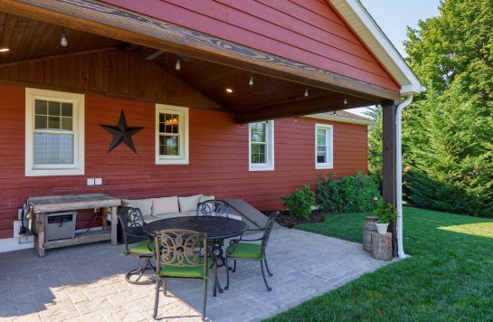 outdoor patio with red wood paneling on side of house and ceiling over patio