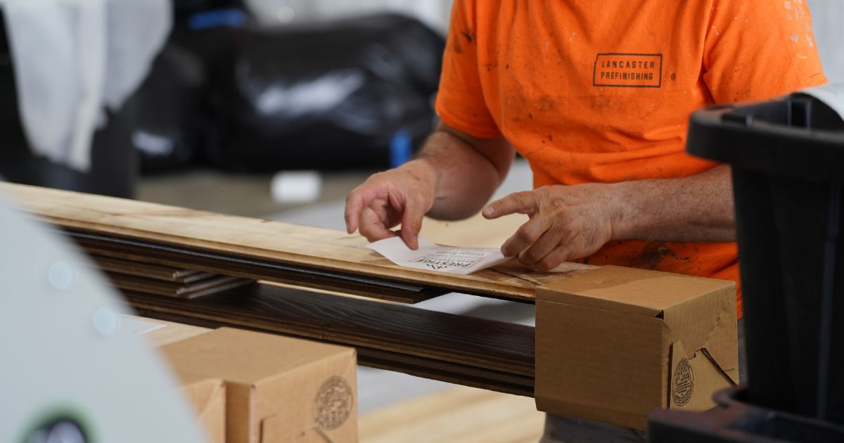 warehouse worker putting a sticker on a boxed order of prefinished wood paneling
