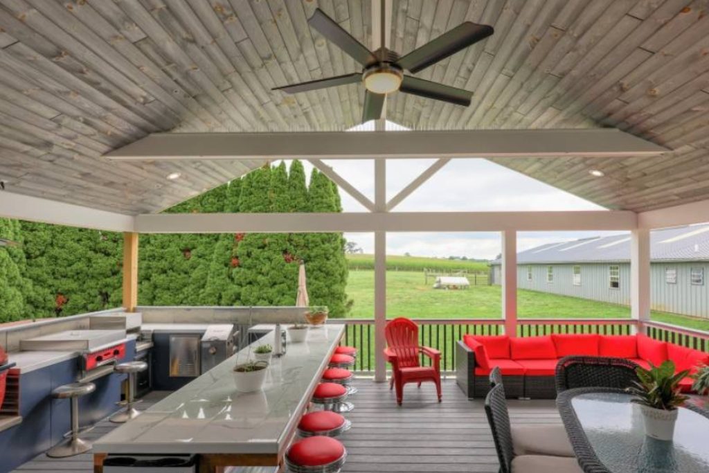 an outdoor kitchen with wood planks for ceiling