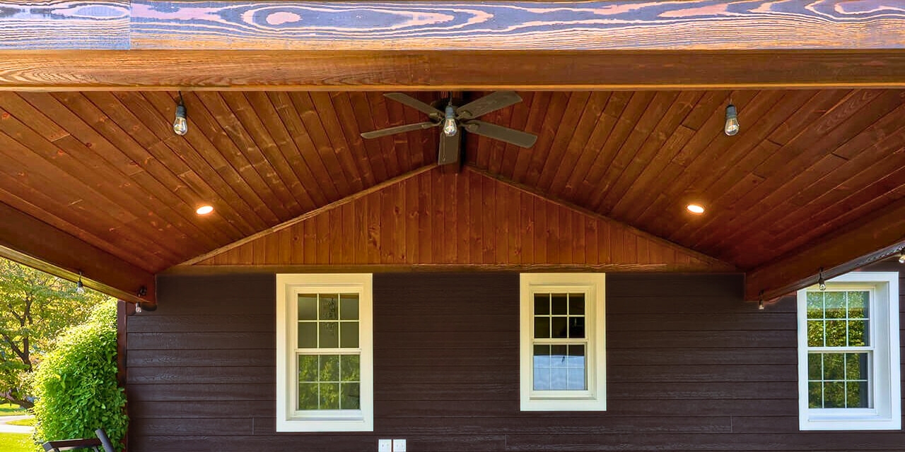 dark-stained wood vaulted ceiling with exposed beams, recessed lighting, and ceiling fan—ideal for DIY vaulted ceiling projects on a covered patio