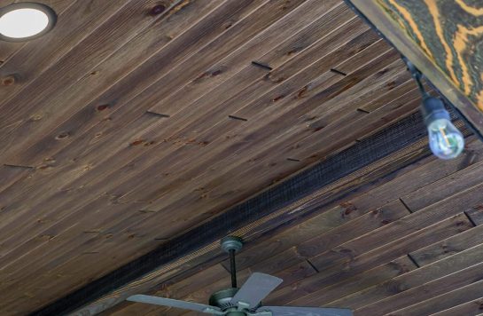 close-up view of dark vintage brown wood plank ceiling with fan and lights