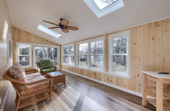 bright sunroom interior walls with prefinished wood paneling and wicker furniture